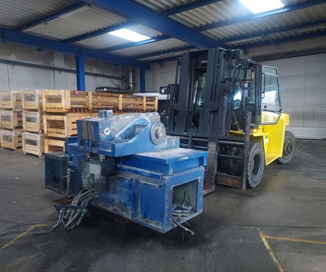 Gabelstapler transportiert alte Maschine in einer Lagerhalle.